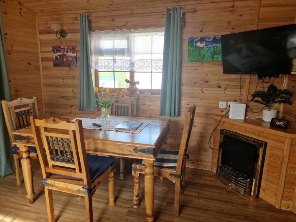 une salle à manger avec une table en bois et une cheminée dans l'établissement Unique Caravan with Outdoor Space Lodge, à Ballantrae