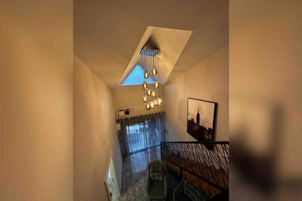 Habitación con escalera, ventana y lámpara de araña. en Kusadasi Guzelcamli Cosy Home, en Kusadasi