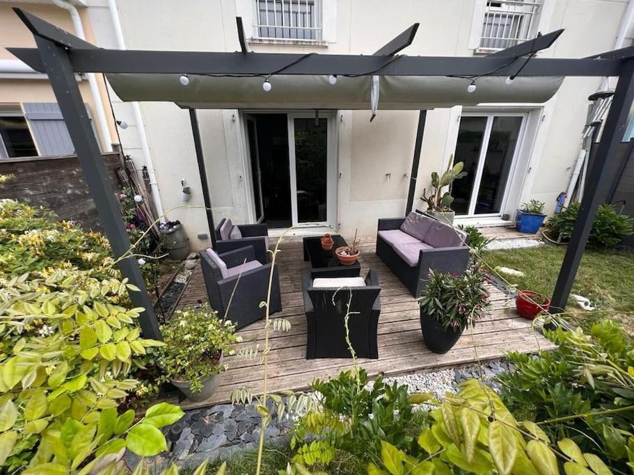 une terrasse en bois avec des chaises et une pergola dans l'établissement Agréable Maison très proche de Tours, à La Riche