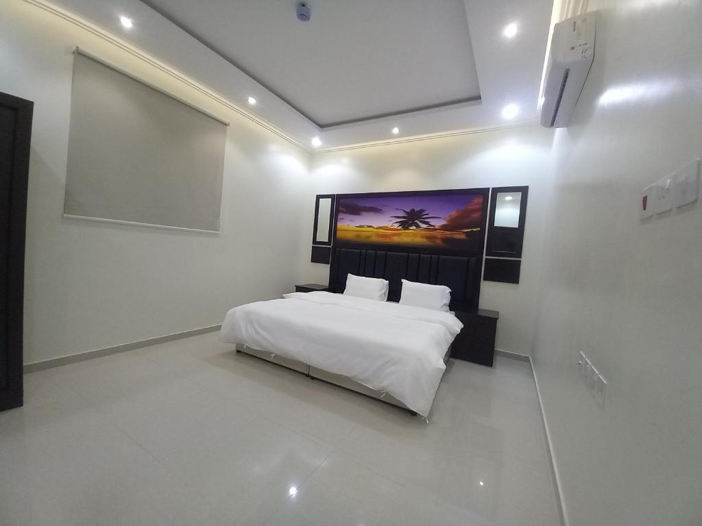 a bedroom with a white bed with a large screen at شقق مفروشة - توافيق in Buraydah