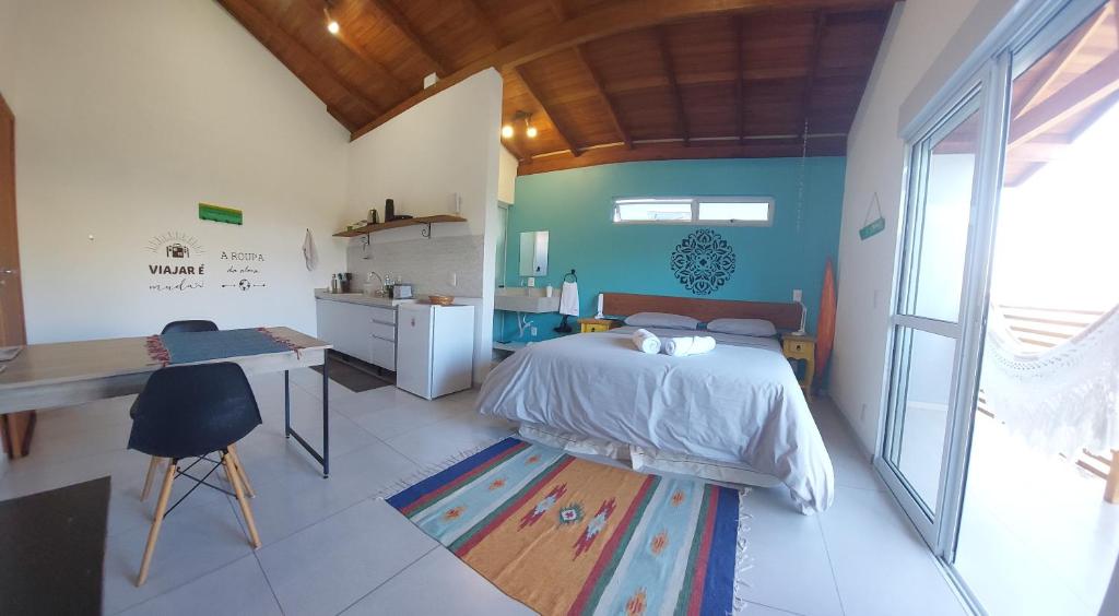 1 dormitorio con cama, escritorio y mesa en Aconchegante suíte com cozinha wifi e estacionamento gratuito Estúdio Mar do Campeche, en Florianópolis