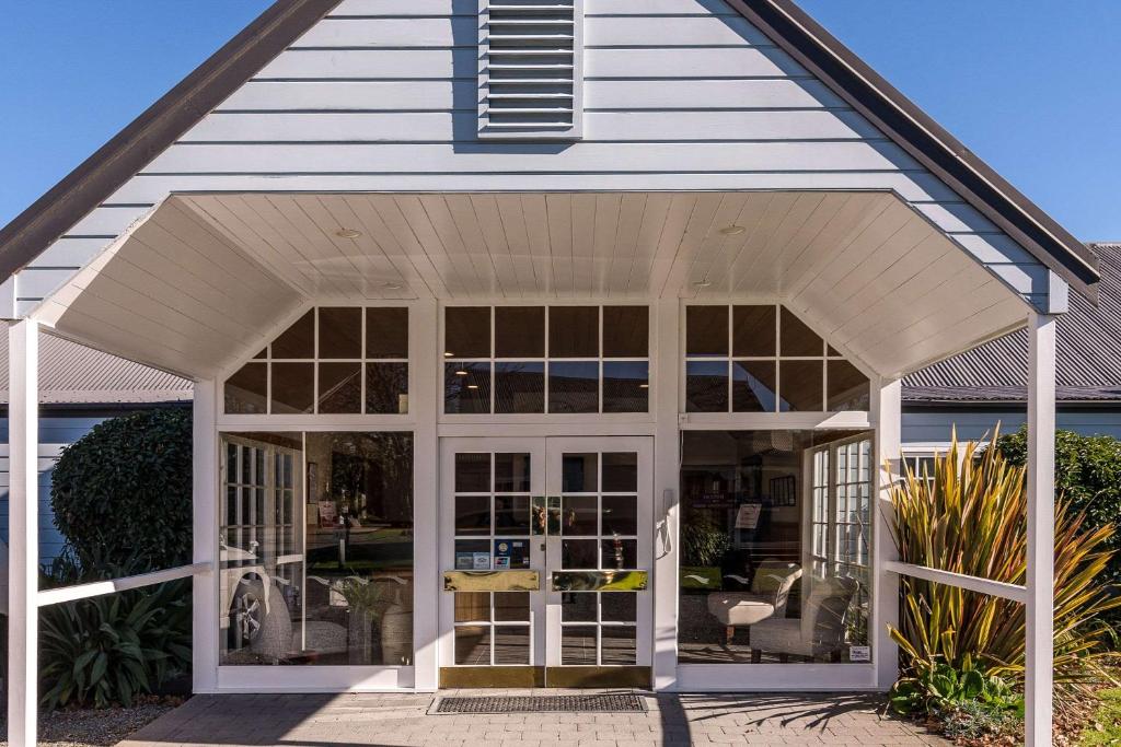 un porche blanco con puertas de cristal en Quality Suites Huka Falls en Taupo