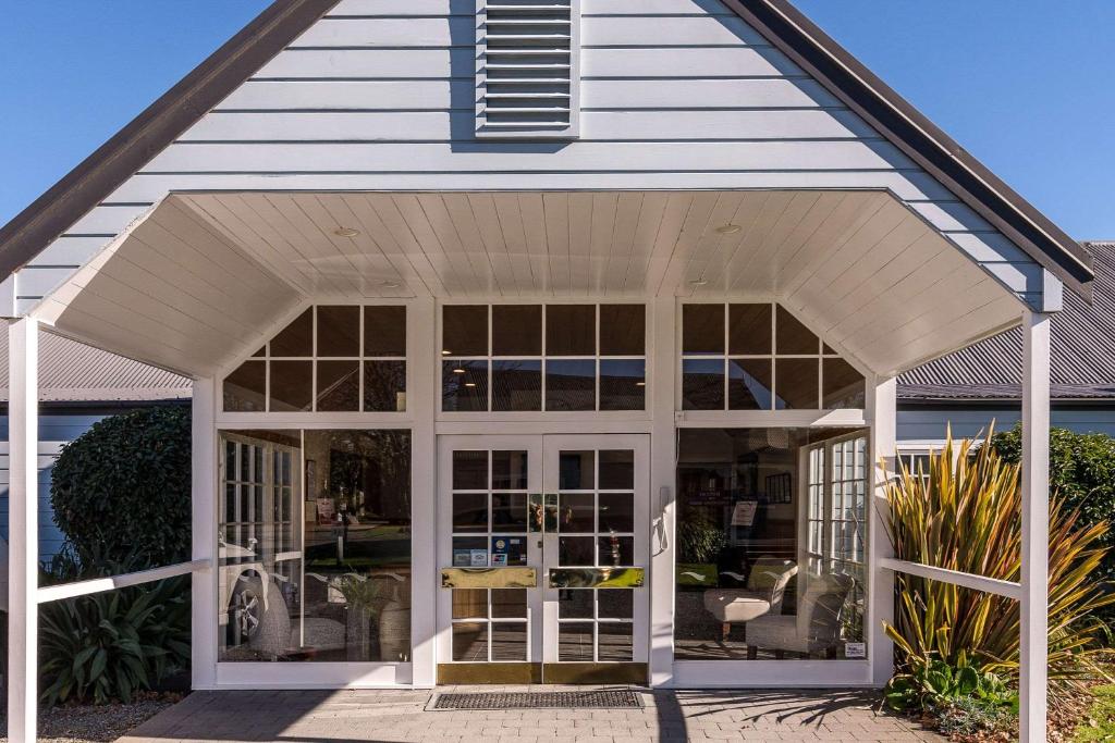 un porche blanco con puertas de cristal en Quality Suites Huka Falls, en Taupo