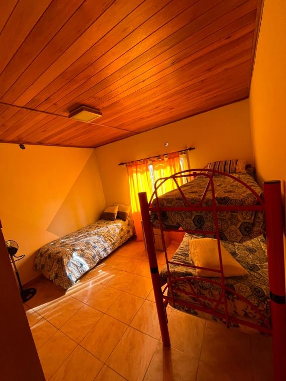 1 dormitorio con 2 camas y techo de madera en Hostal del sol temporario en Rosario