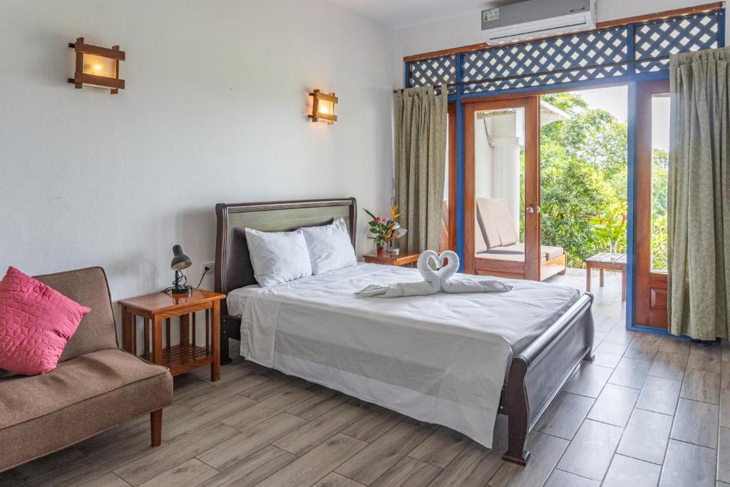 1 dormitorio con cama, sofá y ventana en Mot Mot Vacation en Sámara