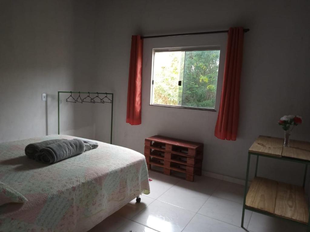 um quarto com uma cama e uma janela com cortinas vermelhas em CASA TEMPORADA DONA CECÍLIA em Cavalcante