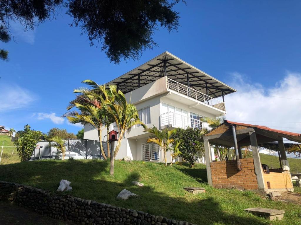 a white house with a palm tree in front of it at Lago calima cabaña in Darién