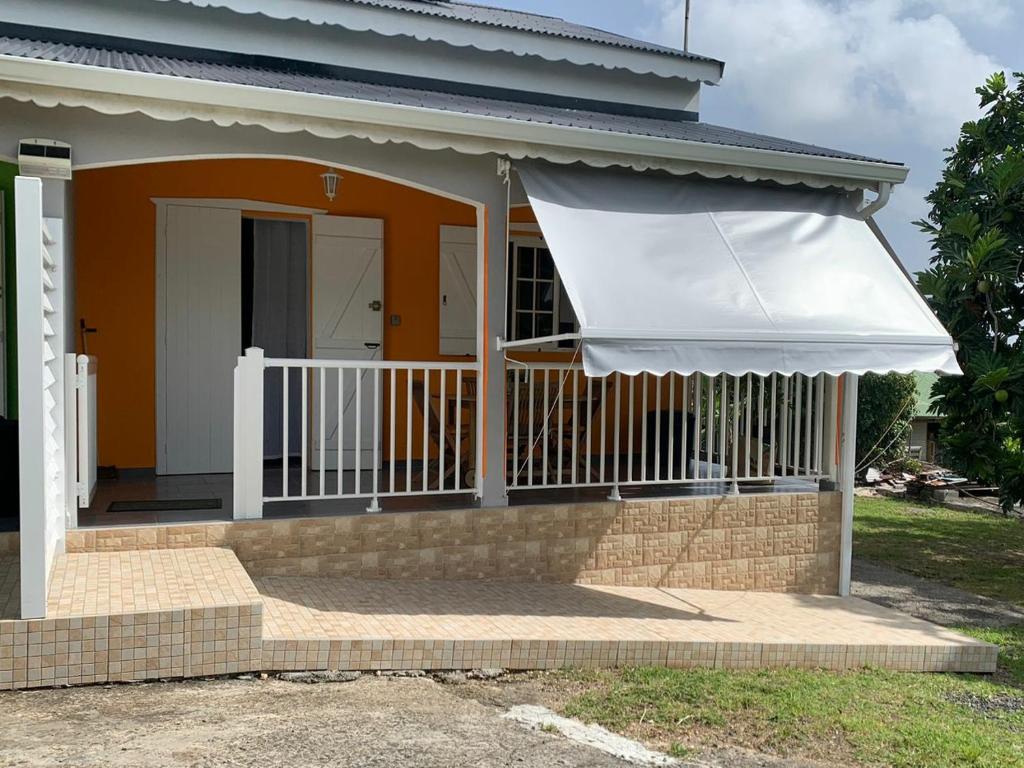 ein Haus mit einer Veranda mit weißem Schatten in der Unterkunft Studio La Félicité in Le Moule