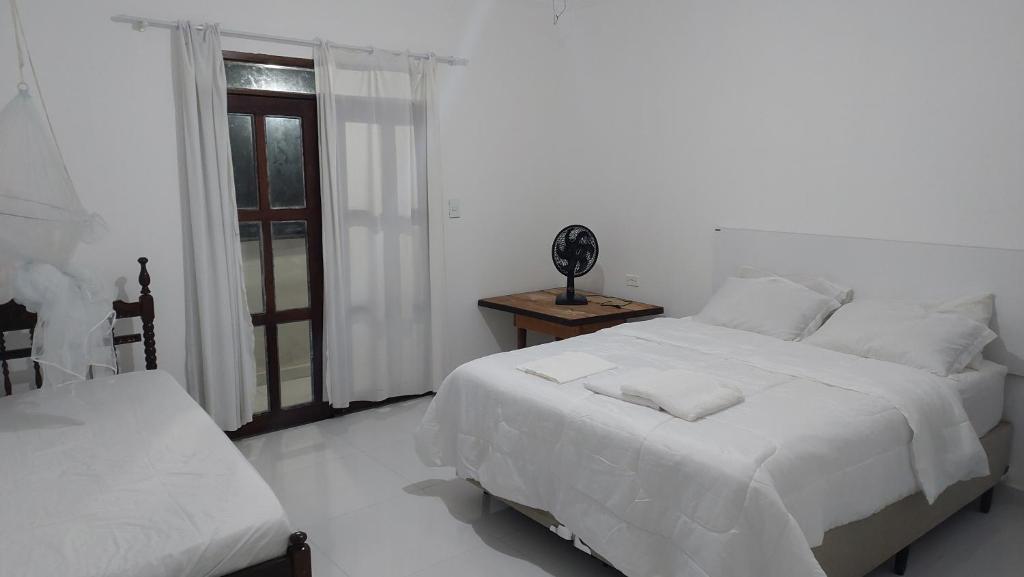 um quarto branco com uma cama e uma janela em Residencial Maria de Lourdes em Ibicoara