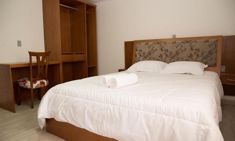 een slaapkamer met een groot bed en 2 handdoeken bij Apartamento Tomasini in Gramado