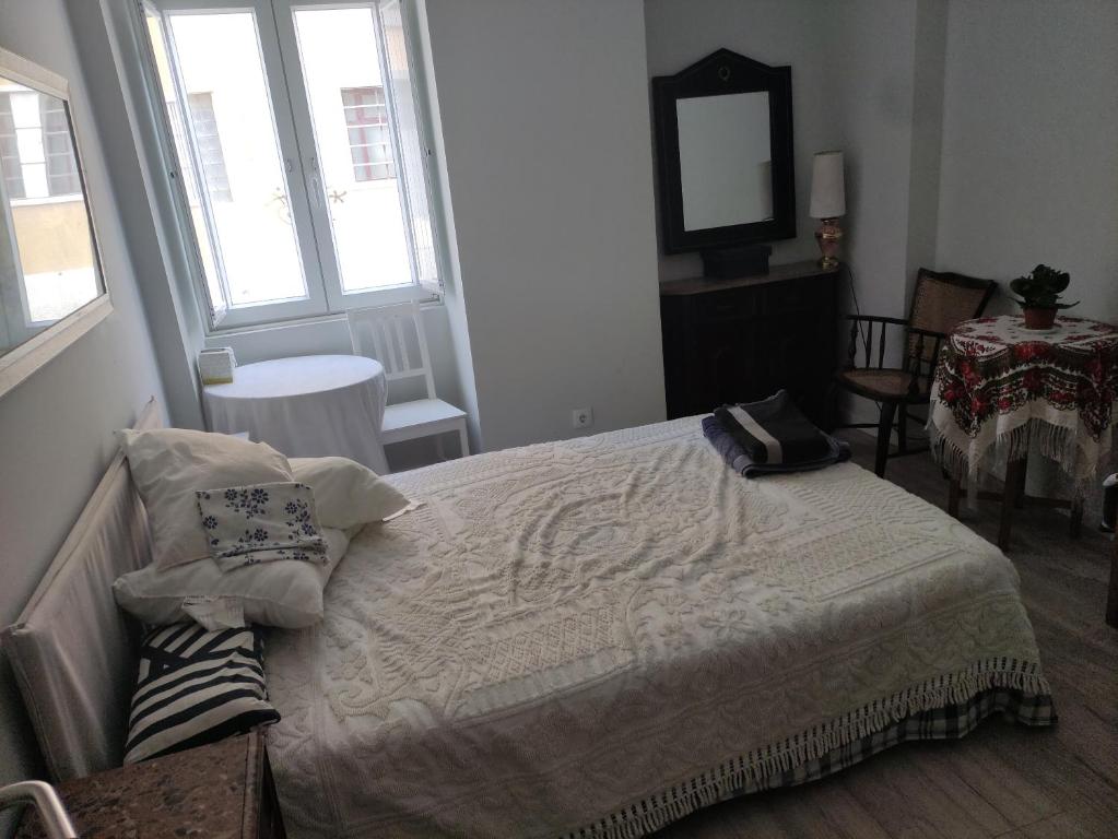 a bedroom with a bed and a mirror and windows at Parede beach in Almada