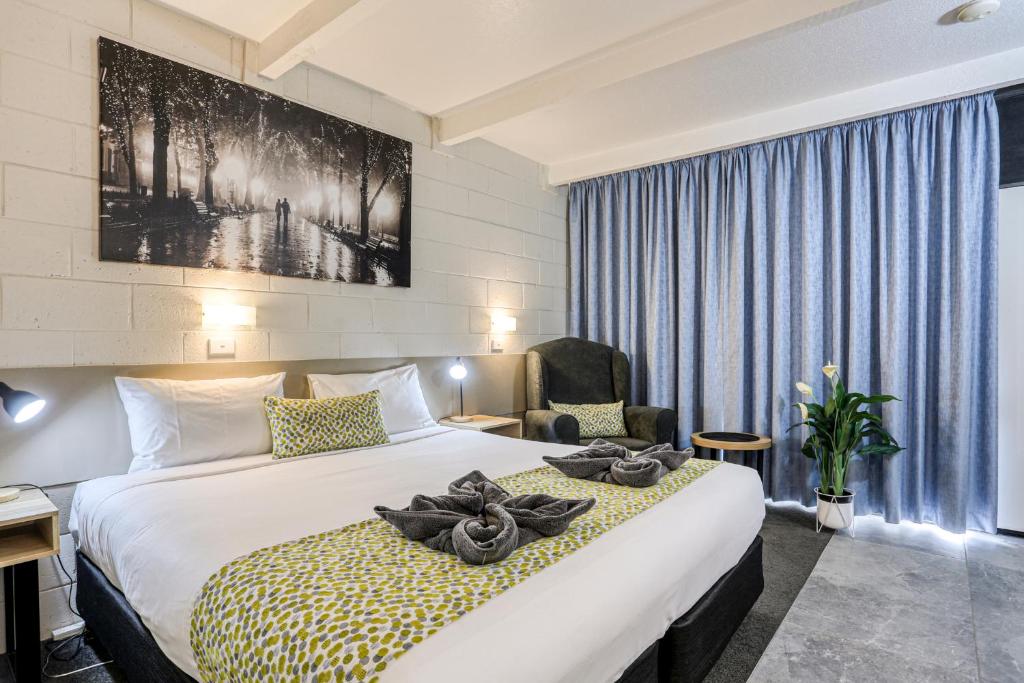 um quarto de hotel com uma cama e uma cadeira em Castle Creek Motel em Euroa