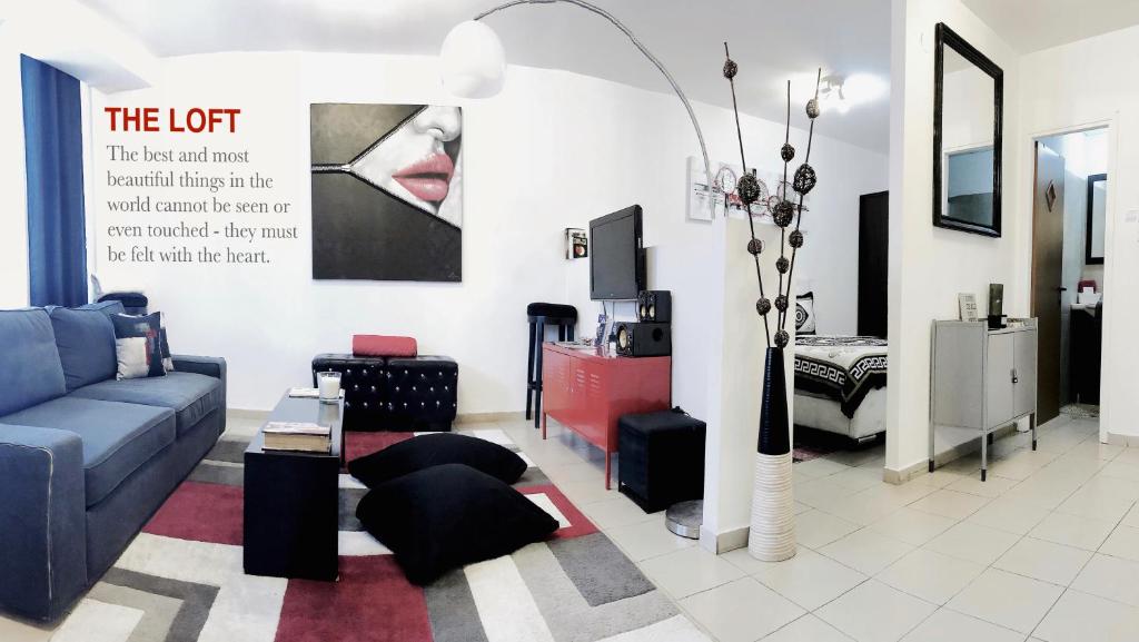 ein Wohnzimmer mit einem blauen Sofa und einem TV in der Unterkunft Stylish Tel Aviv in Tel Aviv