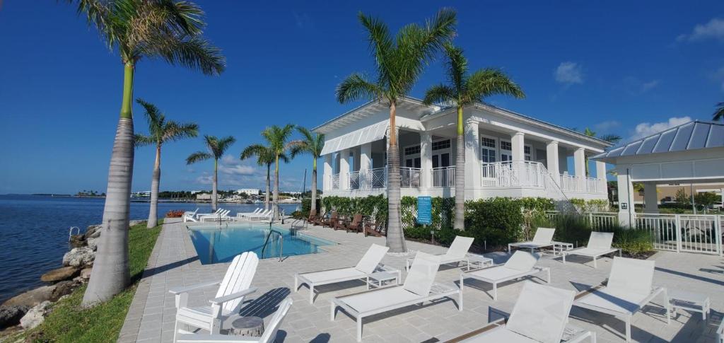una casa con sillas blancas y piscina en Oceans Edge Clubhouse, en Cayo Largo