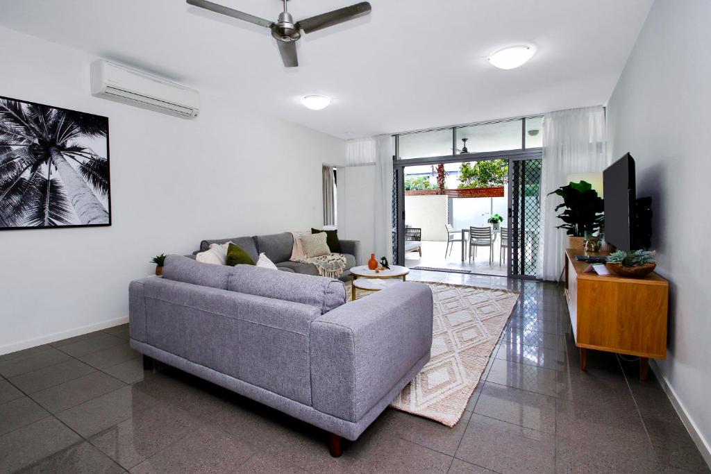 a living room with a gray couch and a tv at Stunning Ground Floor City Apartment 104 in Cairns