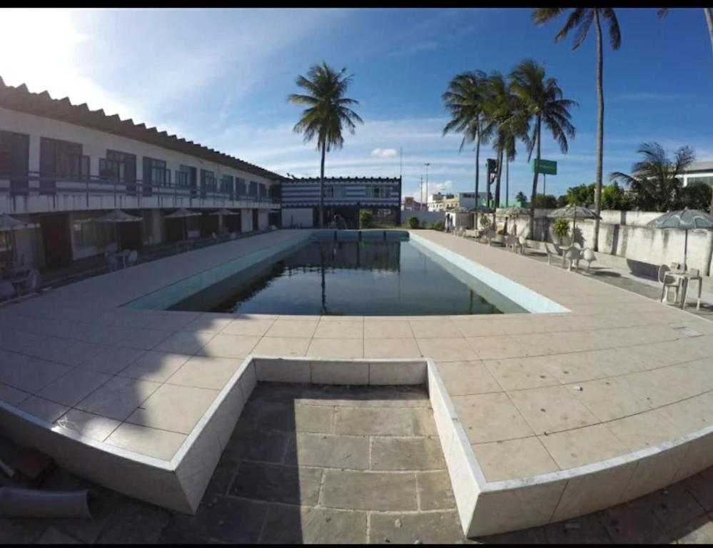 a swimming pool with palm trees and a building at Pousada do Goiano in Cabo Frio