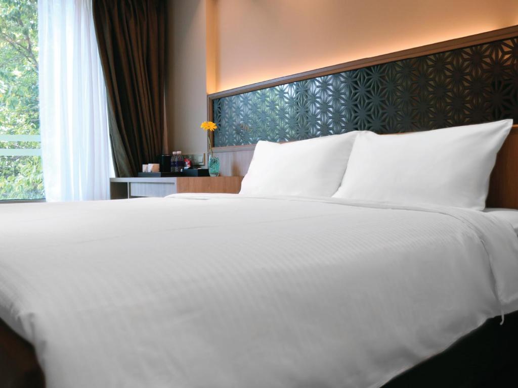 a large white bed in a room with a window at Aqueen Prestige Hotel Jalan Besar in Singapore