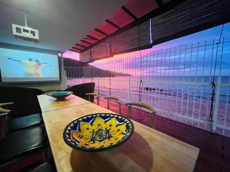 a dining room with a table and a projection screen at Private Beach-front Haven by StayCo - Seaview Pool, KTV & Speaker System, Beach Air Loft, Private Beach Access and Beyond! in Tanjung Bungah