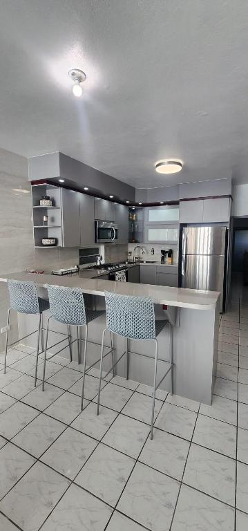 a kitchen with a counter and chairs in it at Kali-Yaiti Casa Vacacional in Vega Baja