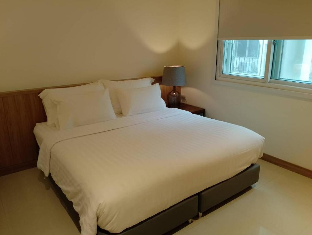 1 cama blanca grande en un dormitorio con ventana en Westerly Hill Pattaya en Pattaya centro