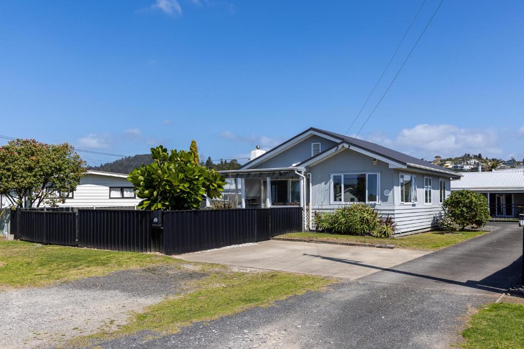 ein weißes Haus mit einem Zaun davor in der Unterkunft Tui nest in Whangamata