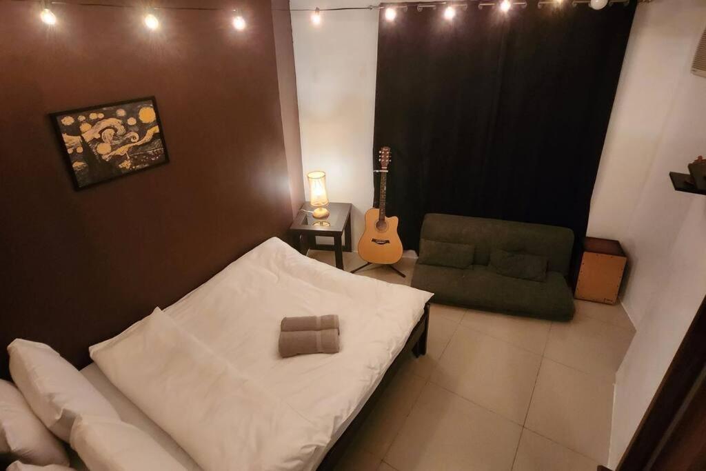 um quarto com uma cama, uma cadeira e uma guitarra em Music Inspired Apartment em Manila