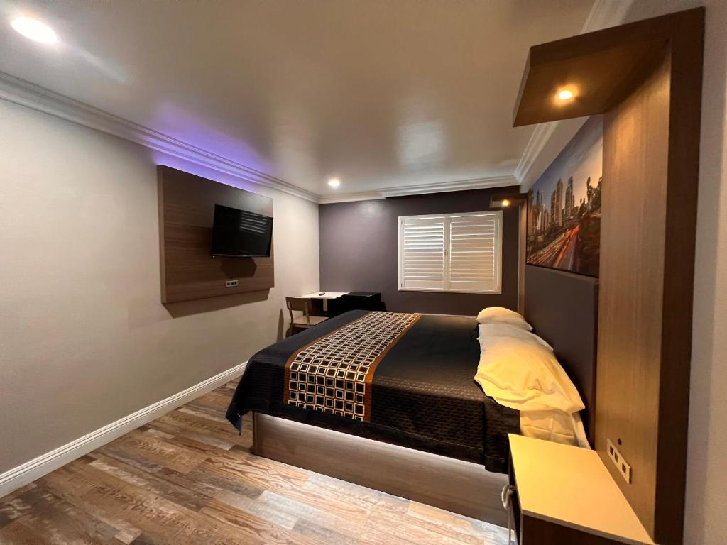 a bedroom with a bed and a desk and a television at The Patio Motel - Los Angeles, LAX in Gardena