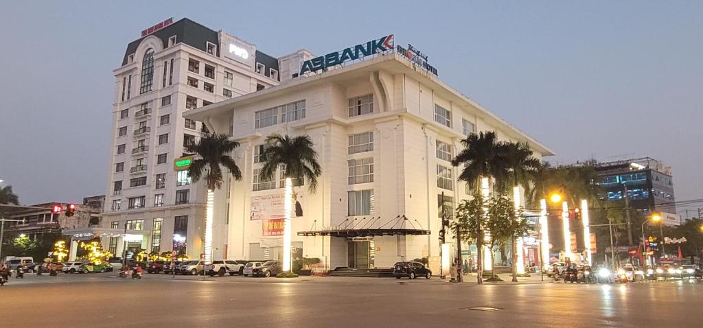 a large white building with palm trees in front of it at Khách sạn Thái Bình Dream in Thái Bình