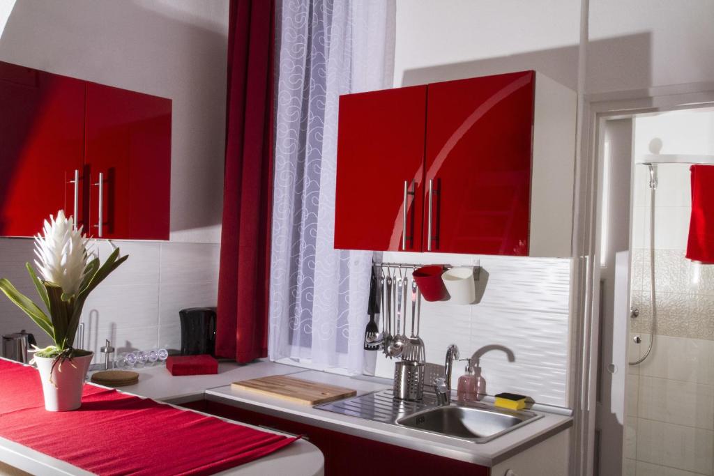 una cucina con armadi rossi e lavandino di Kálmán Apartman a Budapest
