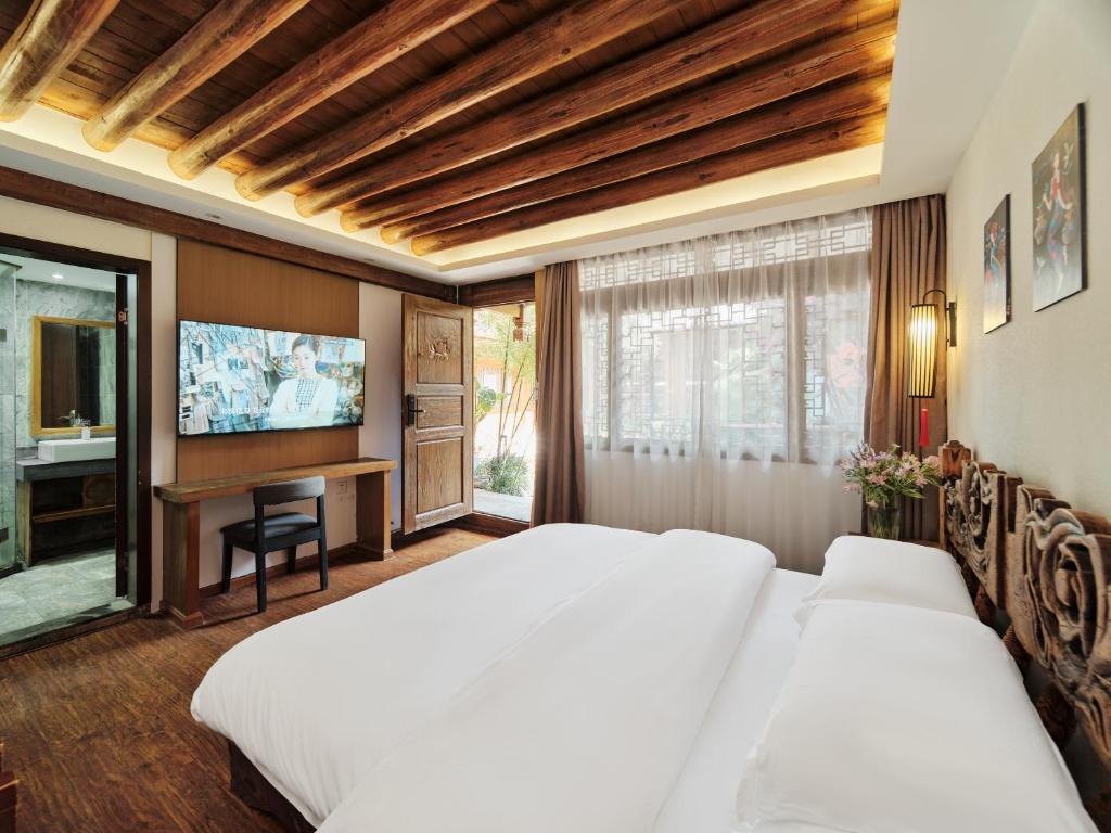 a bedroom with two beds and a flat screen tv at Xilu Xiaoxie Inn in Lijiang