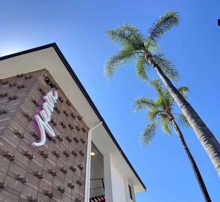 洛杉磯的住宿－Fenix Hotel Hollywood，棕榈树旁的一座建筑,上面有恐龙标志
