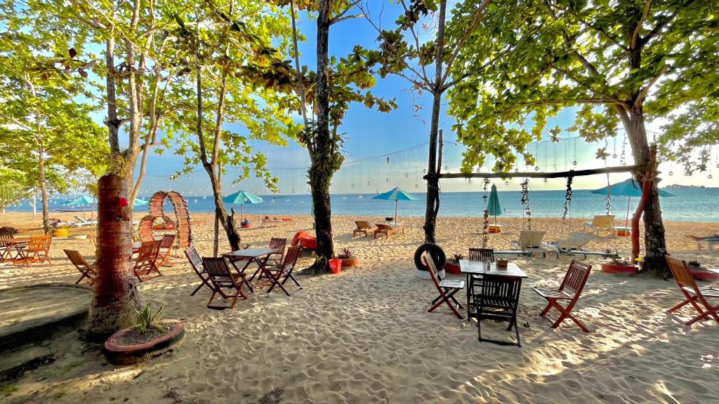 a group of chairs and tables on a beach at Vung Bau Resort in Phú Quốc
