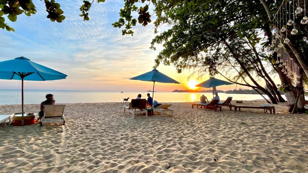 a group of people sitting under umbrellas on a beach at Vung Bau Resort in Phú Quốc