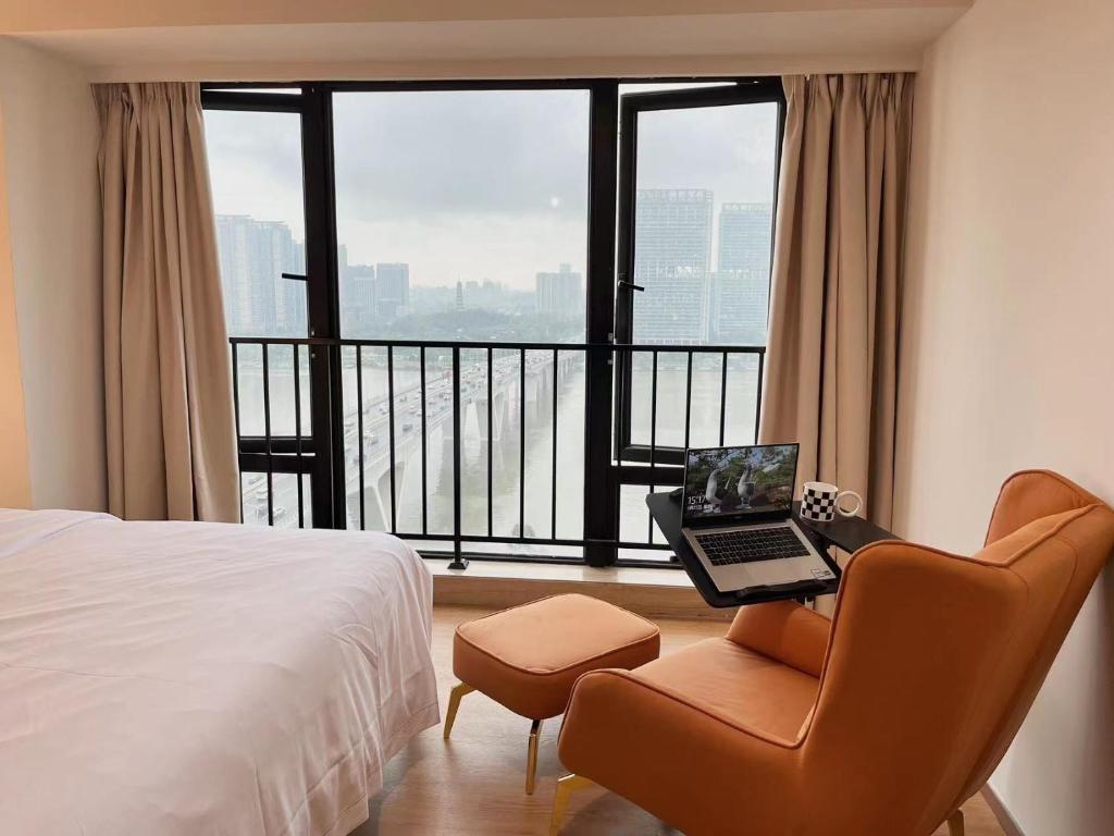 a bedroom with a desk with a laptop and a chair at Manriver Executive Apartments in Guangzhou