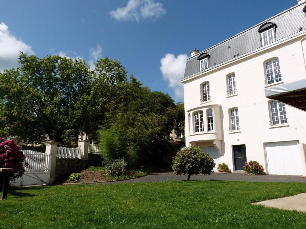 una gran casa blanca con un patio de césped en Vintage holiday apartment on the 1st floor of an elegant mansion - Coutances, en Coutances