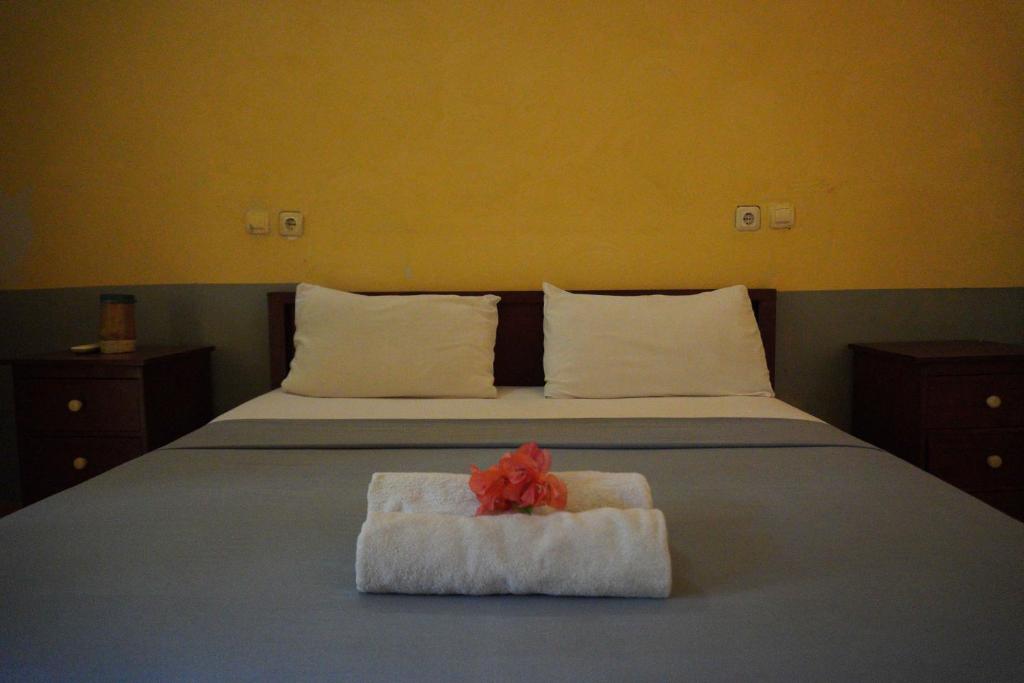 - un lit avec une serviette blanche et une fleur rouge dans l'établissement Kiayazo ViBES Inn, à Gili Trawangan