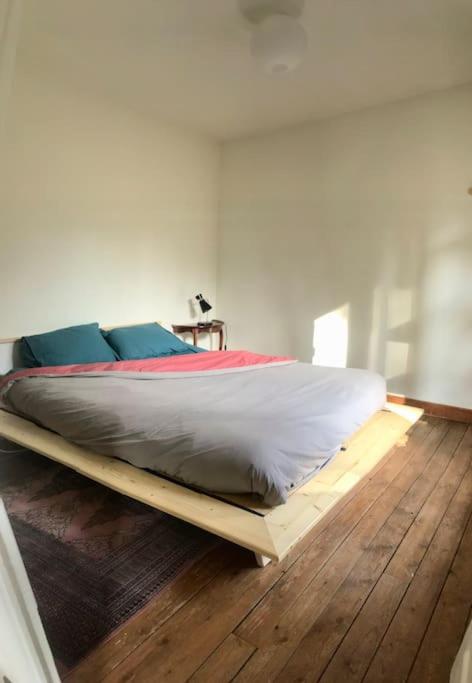 a bed on a wooden floor in a room at Maison chaleureuse et calme in Panazol