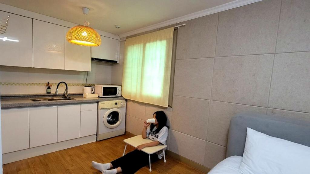 a woman sitting in a chair in a kitchen at Stay 230 in Danyang