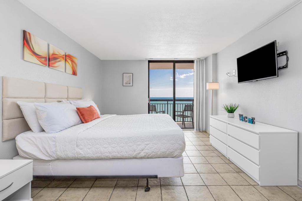 a white bedroom with a bed and a flat screen tv at Romantic Oceanfront Studio Escape w Perfect View 1212 in Myrtle Beach