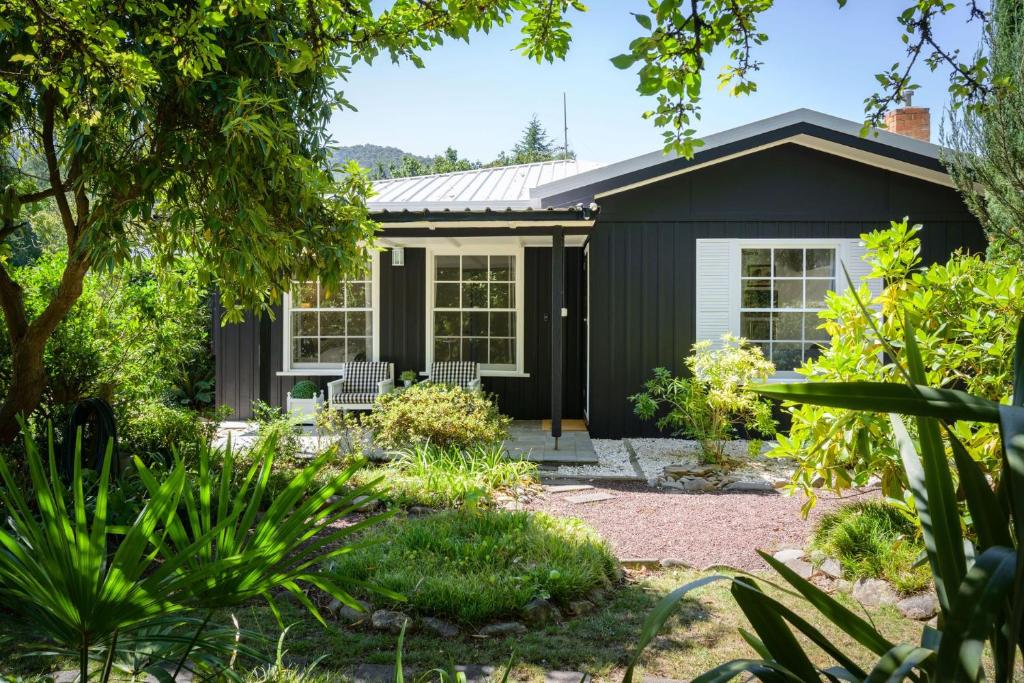 a black house with a garden in front of it at Golden Pine Retreat in Bright