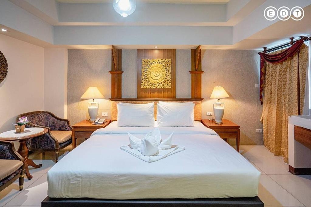 a hotel room with a large bed with two chairs at Kim Hotel At Morleng in Bangkok