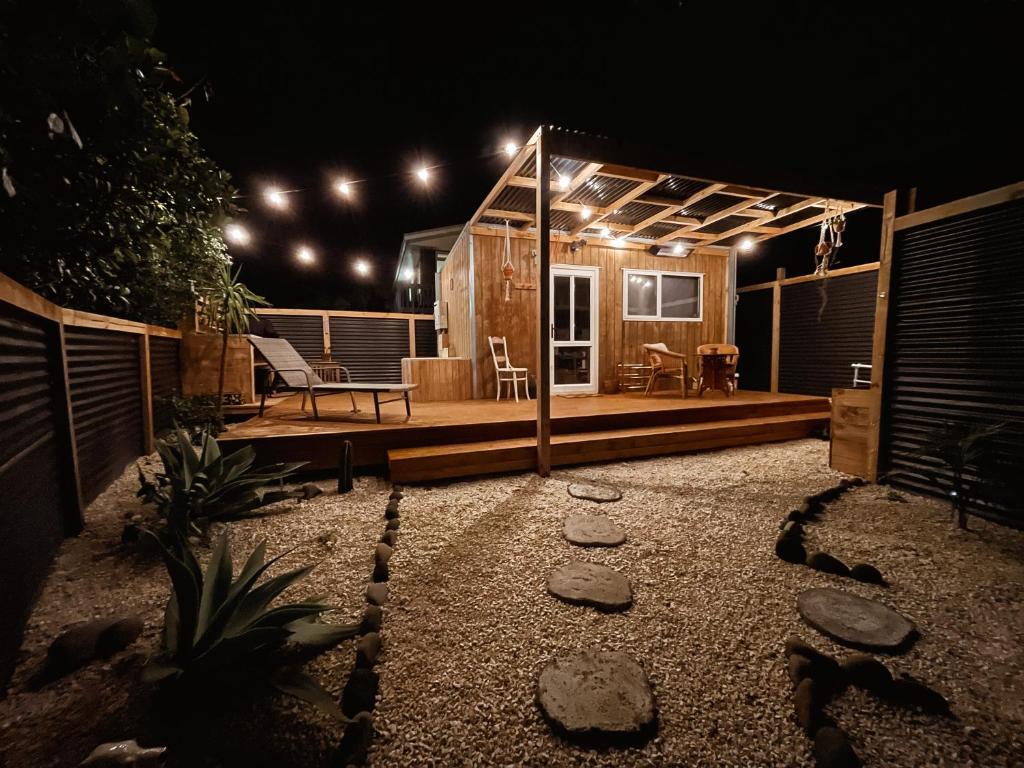 un patio trasero con una casa con terraza por la noche en The Secret Studio, Outdoor Bath & Pizza Oven, en New Plymouth