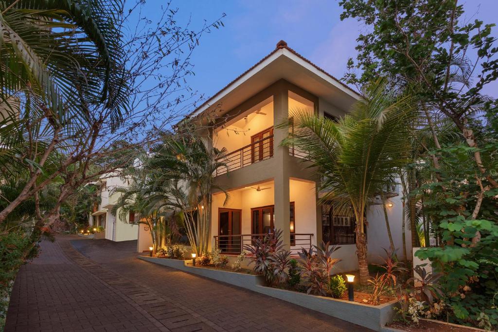 a house with palm trees in front of it at 3 Solace3 BR PvtPool Villa wCook Candolim Goa in Candolim
