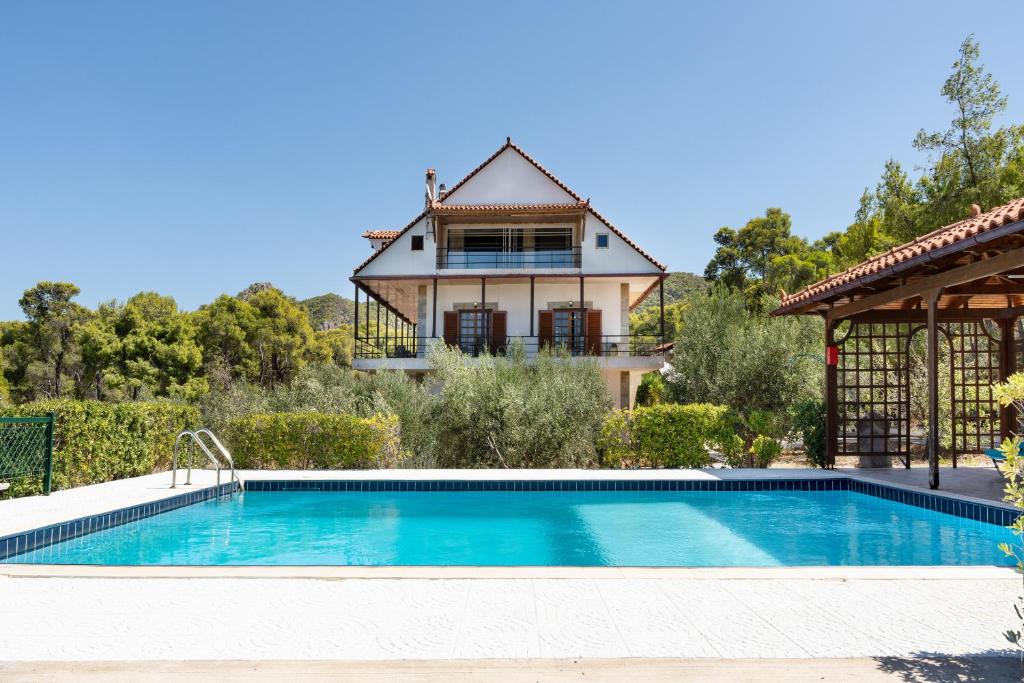 a villa with a swimming pool in front of a house at Villa Sterna in Loutraki