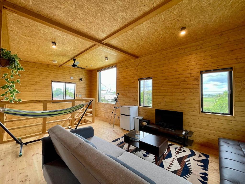 a living room with a couch and a hammock at Kujukuri SOSA -九十九里 海辺のコテージ SOSA- in Sosa