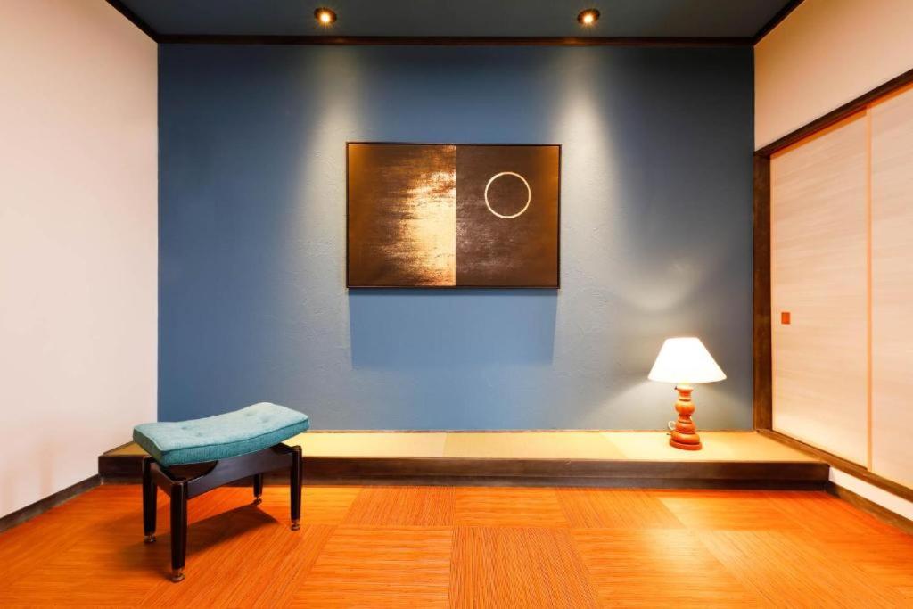 una stanza con una parete blu con una sedia e una lampada di Mahana Ito a Ito