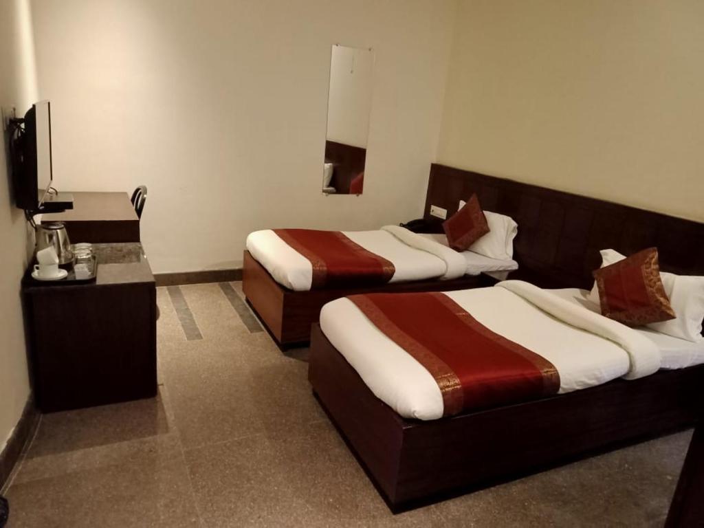um quarto de hotel com duas camas e uma televisão em Hotel Atlantis em Varanasi