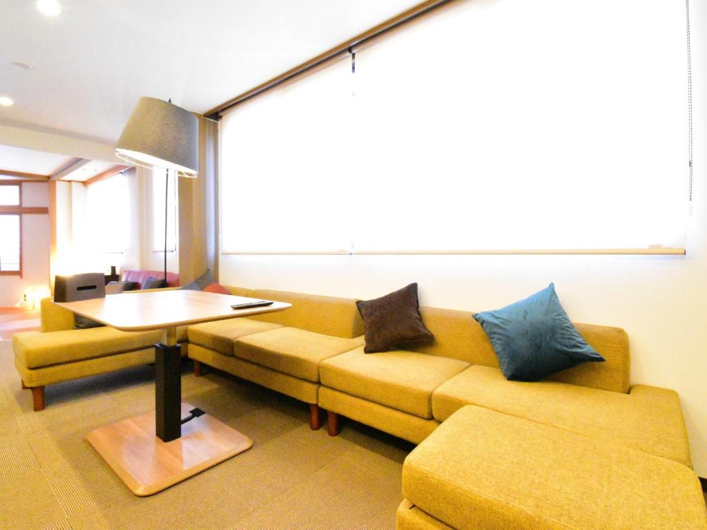 uma sala de estar com um sofá amarelo e uma mesa em The Garden Place Hiroshima - Vacation STAY 89703v em Hiroshima