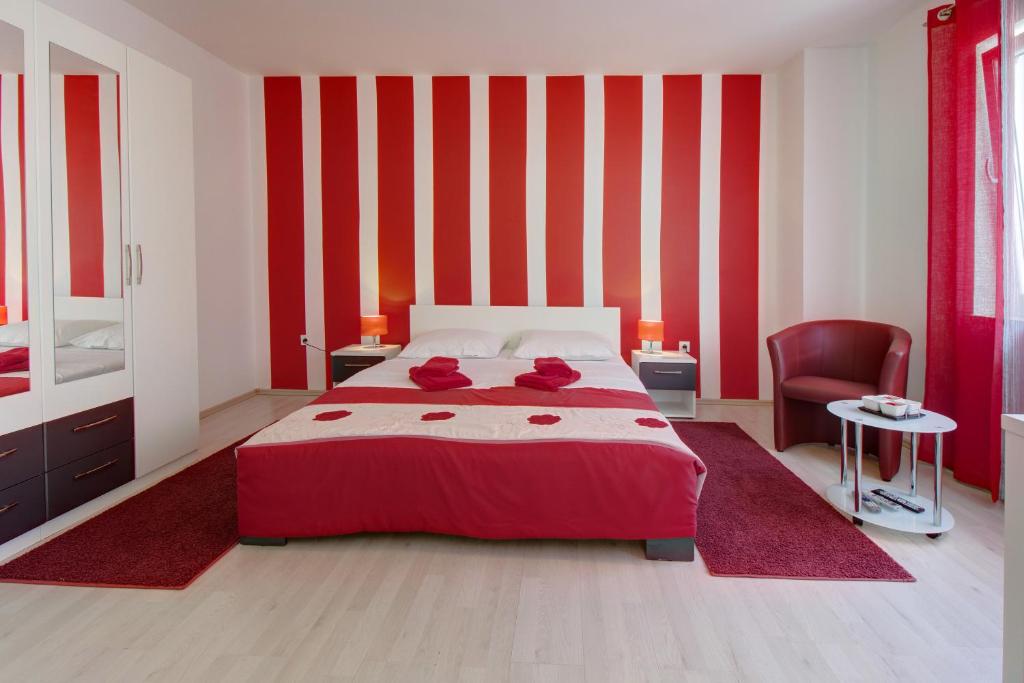a red and white bedroom with a bed and a chair at Apartment Nikolina in Mali Lošinj