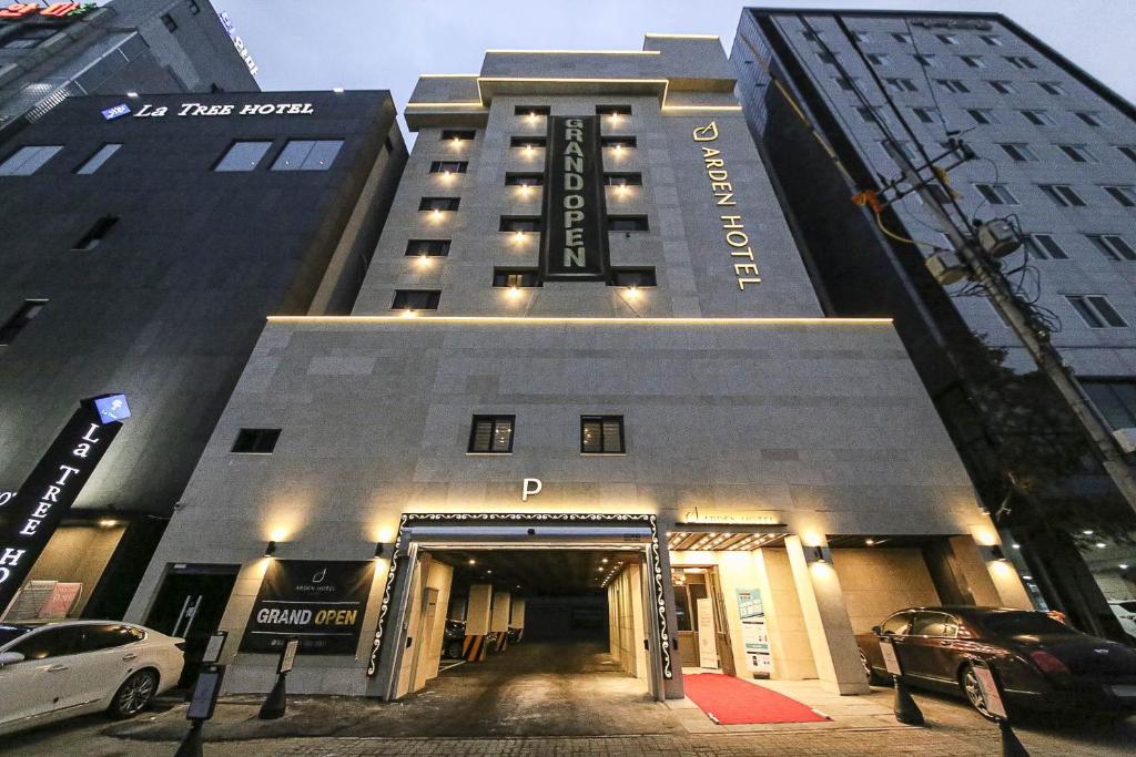 a large building with a parking garage in front of it at Aden Hotel in Cheonan